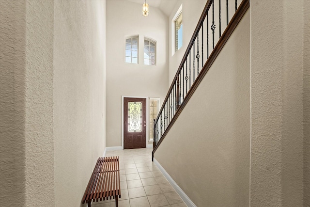9933 Cottontail Ln, Mckinney, TX 75071 - entrance foyer featuring a textured wall, healthy amount of natural light, a high ceiling, light tile patterned floors, and baseboards