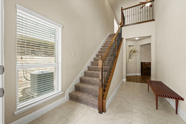 9933 Cottontail Ln, Mckinney, TX 75071 - staircase with healthy amount of natural light, baseboards, tile patterned flooring, and a towering ceiling