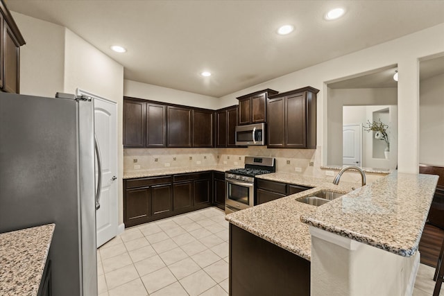 9933 Cottontail Ln, Mckinney, TX 75071 - kitchen featuring stainless steel appliances, a sink, dark brown cabinetry, a peninsula, and recessed lighting