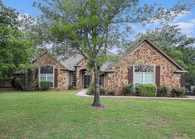 view of front of house with fence, a front yard, and stone siding