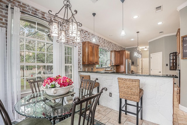 kitchen with brown cabinetry, decorative light fixtures, visible vents, a chandelier, and ornamental molding