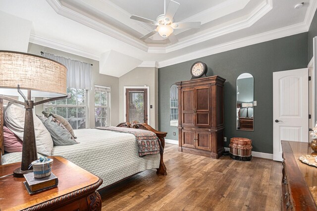 bedroom featuring ornamental molding, wood finished floors, baseboards, ceiling fan, and a tray ceiling