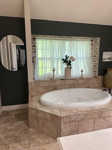 full bathroom with baseboards and a garden tub