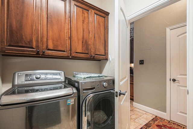 clothes washing area featuring cabinet space, baseboards, and washer and clothes dryer