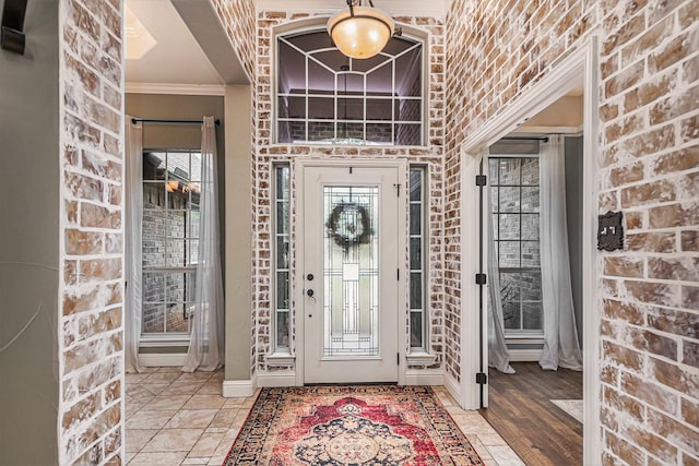 entryway featuring crown molding, baseboards, and brick wall