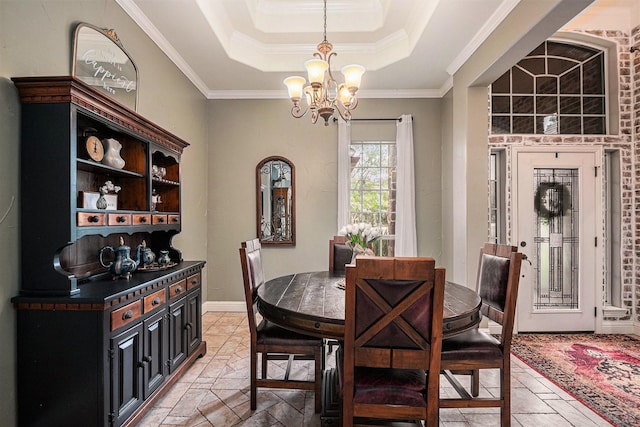 dining room with an inviting chandelier, a raised ceiling, and crown molding