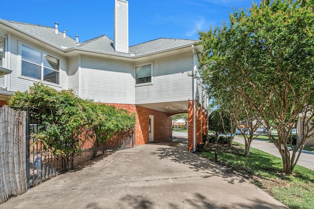 2085 Idlewood Dr, Grapevine, TX 76051 - view of side of home with a carport, brick siding, a chimney, and driveway