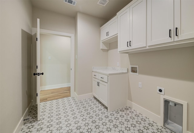 laundry area with cabinet space, electric dryer hookup, visible vents, and baseboards