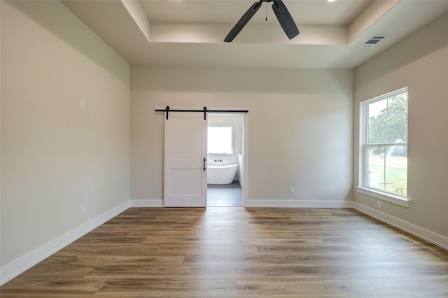 unfurnished room featuring visible vents, a tray ceiling, and a healthy amount of sunlight