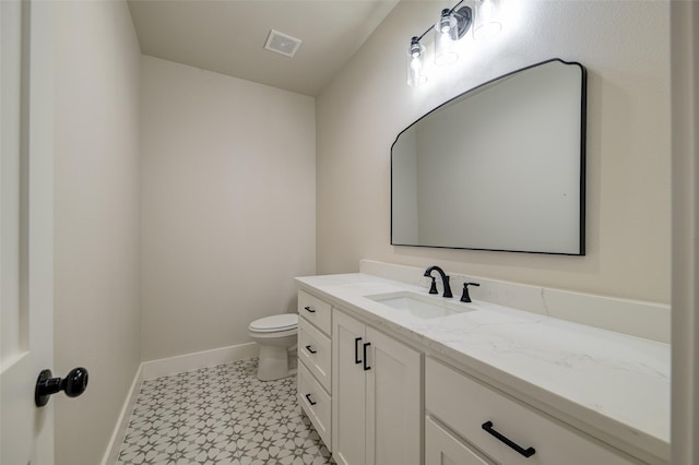 bathroom featuring visible vents, vanity, toilet, baseboards, and tile patterned floors