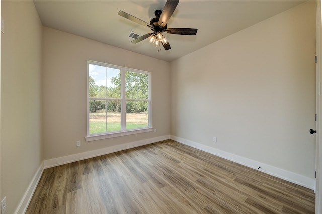 spare room with baseboards, a ceiling fan, light wood-type flooring, and visible vents