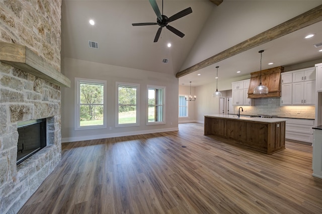 kitchen with open floor plan, a fireplace, custom exhaust hood, and high vaulted ceiling