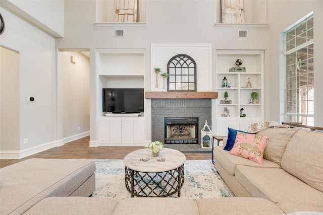1355 Crockett Dr, Frisco, TX 75033 - living room with built in shelves, wood finished floors, baseboards, a fireplace, and a high ceiling