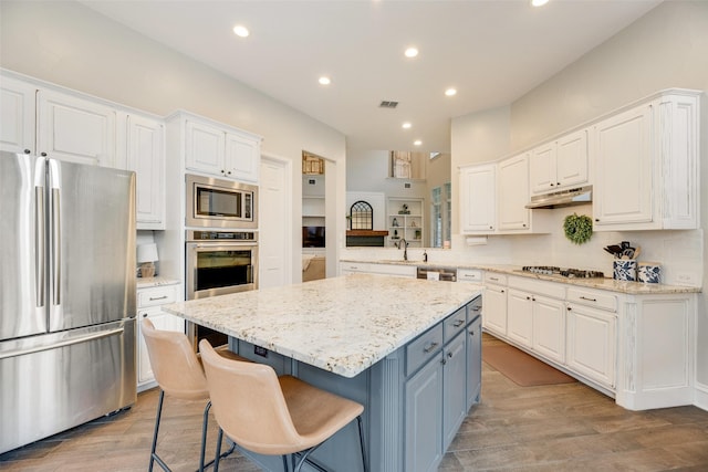 1355 Crockett Dr, Frisco, TX 75033 - kitchen featuring appliances with stainless steel finishes, white cabinets, a center island, light wood-style floors, and recessed lighting