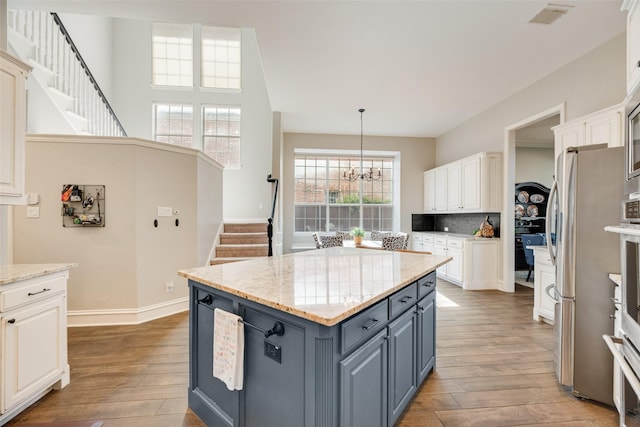 1355 Crockett Dr, Frisco, TX 75033 - kitchen featuring white cabinetry, a chandelier, light wood finished floors, a center island, and backsplash