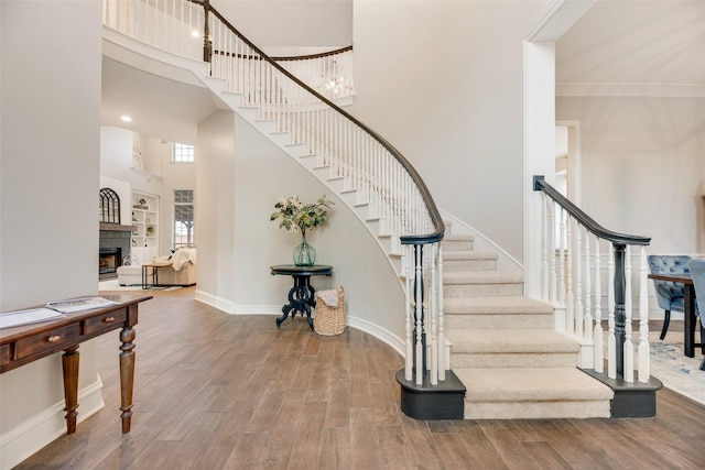 1355 Crockett Dr, Frisco, TX 75033 - staircase with wood finished floors, baseboards, a fireplace, a high ceiling, and crown molding
