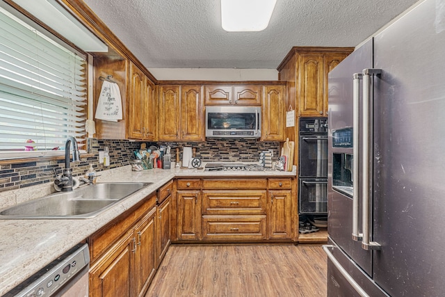 372 County Road 477, Stephenville, TX 76401 - kitchen featuring light wood-style floors, a textured ceiling, brown cabinets, a sink, and stainless steel appliances