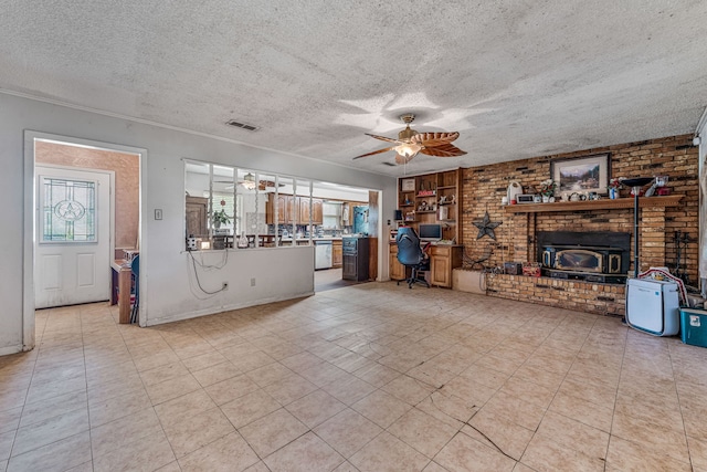 372 County Road 477, Stephenville, TX 76401 - unfurnished living room featuring visible vents, a wood stove, brick wall, ceiling fan, and a textured ceiling