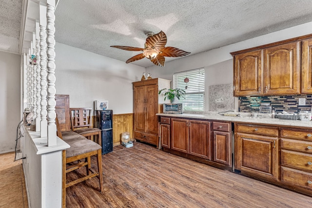 372 County Road 477, Stephenville, TX 76401 - kitchen with brown cabinetry, a textured ceiling, ceiling fan, and wainscoting