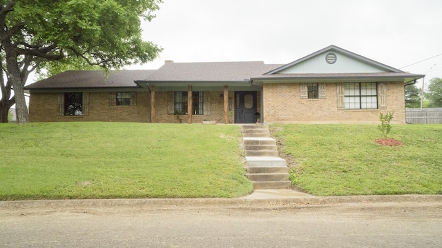 ranch-style home with brick siding, fence, and a front yard