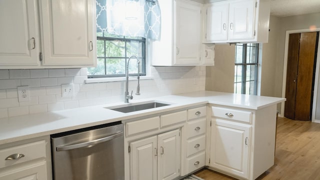 kitchen with light wood-style floors, white cabinets, tasteful backsplash, and dishwasher