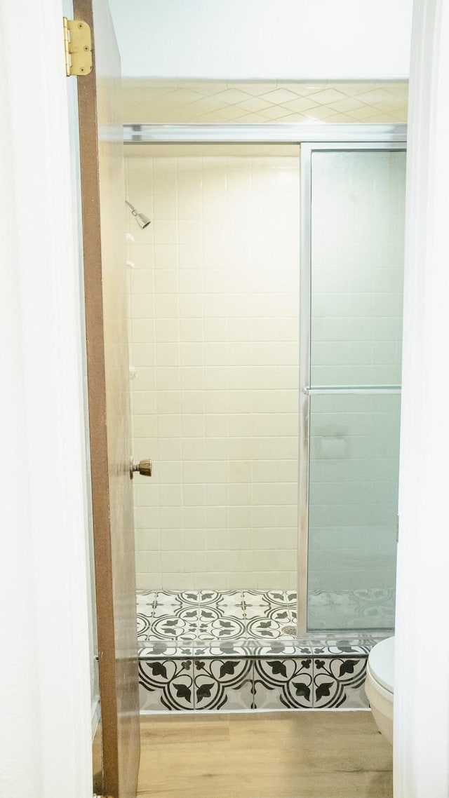 bathroom with wood finished floors, a stall shower, and toilet
