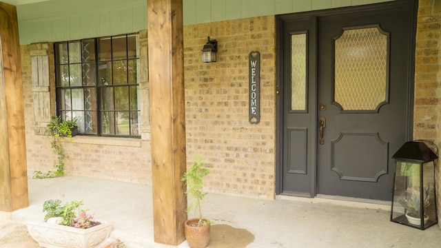 entrance to property with brick siding and a porch