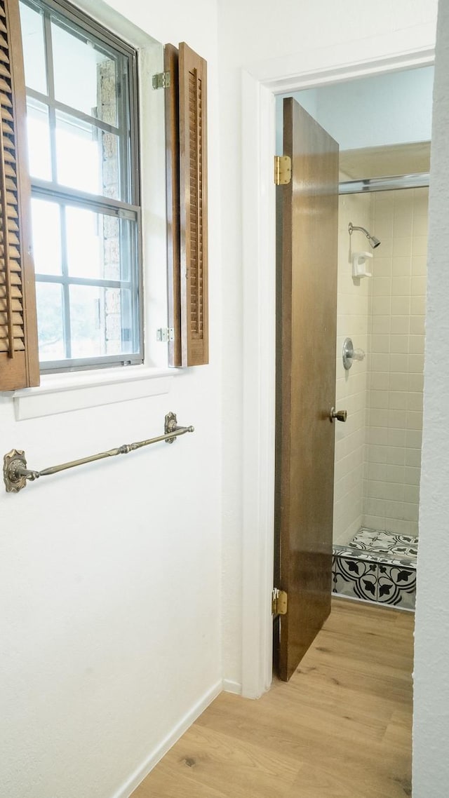 bathroom with baseboards, a shower stall, and wood finished floors