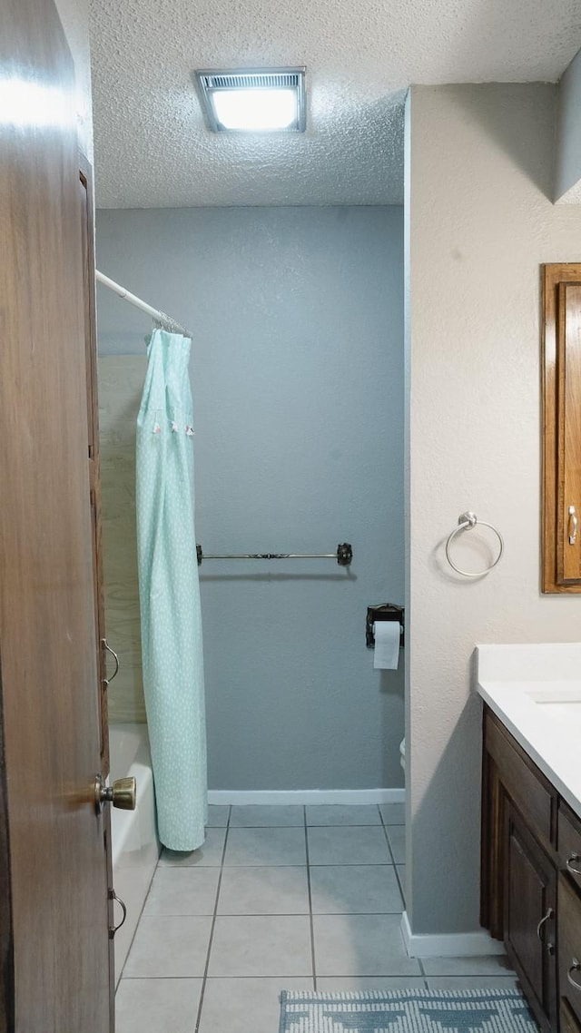 bathroom featuring vanity, a textured ceiling, baseboards, and shower / bath combo