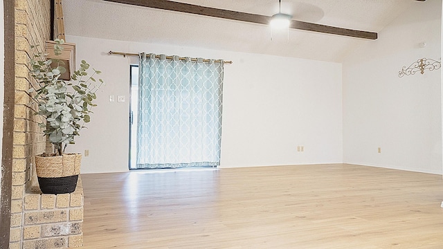 spare room with a ceiling fan, vaulted ceiling with beams, and wood finished floors
