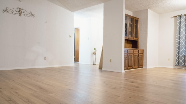 unfurnished room featuring a textured ceiling, baseboards, and light wood finished floors