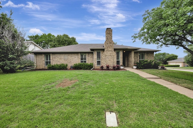 ranch-style house with roof with shingles, a chimney, a front lawn, and brick siding