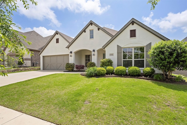 french provincial home with brick siding, an attached garage, a front yard, and concrete driveway