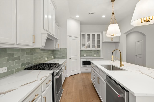 kitchen featuring a sink, light wood finished floors, stainless steel appliances, recessed lighting, and white cabinetry