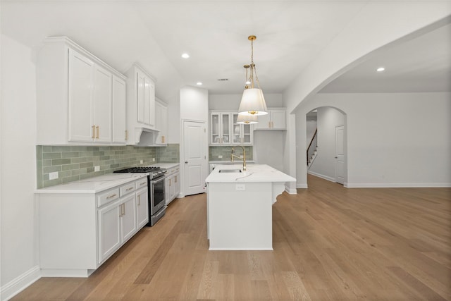 kitchen featuring a sink, high end stainless steel range, backsplash, and white cabinets