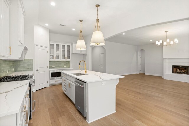 kitchen with visible vents, a sink, tasteful backsplash, arched walkways, and stainless steel appliances