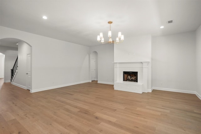 unfurnished living room featuring arched walkways, baseboards, light wood finished floors, and visible vents