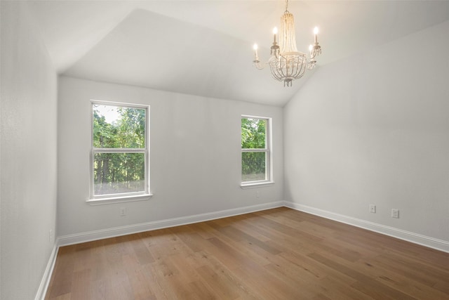 spare room featuring baseboards, vaulted ceiling, wood finished floors, and a notable chandelier