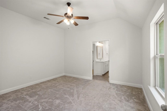 unfurnished bedroom with light colored carpet, a sink, baseboards, vaulted ceiling, and visible vents