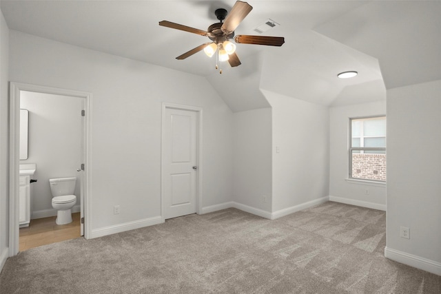 additional living space featuring visible vents, lofted ceiling, baseboards, light colored carpet, and a ceiling fan