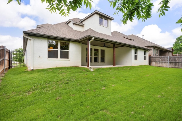 back of property with a lawn, ceiling fan, a fenced backyard, and roof with shingles