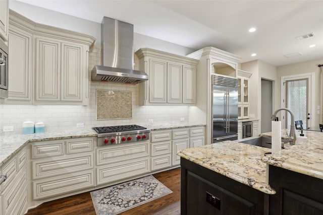 kitchen featuring wall chimney range hood, appliances with stainless steel finishes, visible vents, and tasteful backsplash