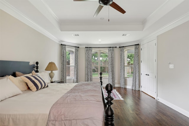 bedroom with visible vents, wood finished floors, and a tray ceiling