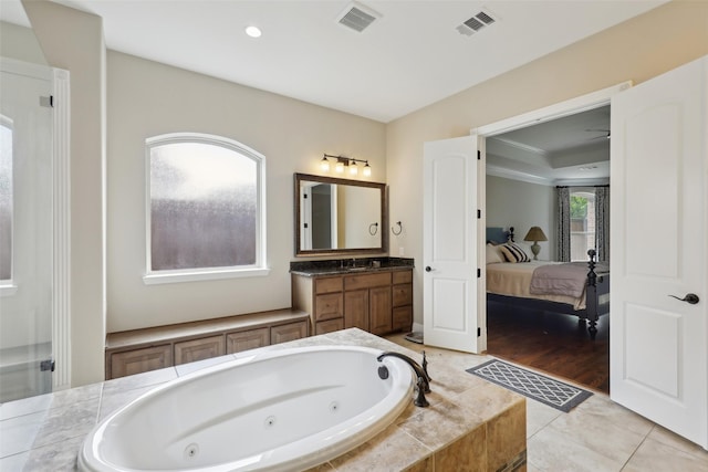 ensuite bathroom with visible vents, connected bathroom, vanity, and a jetted tub