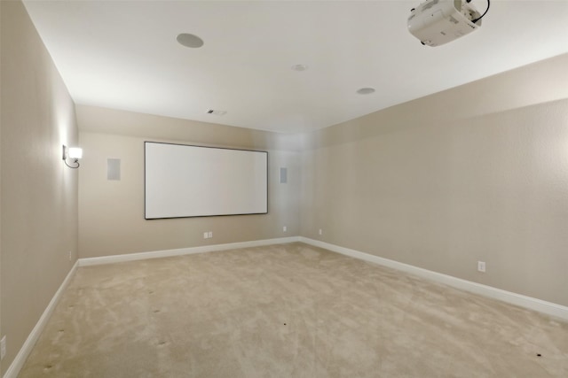 cinema room featuring baseboards, visible vents, and light carpet