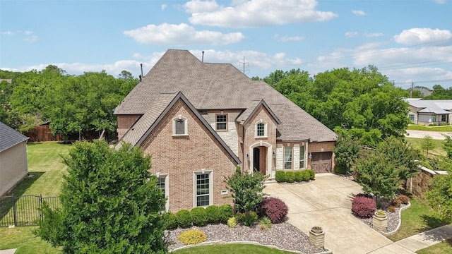 french provincial home featuring brick siding, fence, a front lawn, concrete driveway, and an attached garage