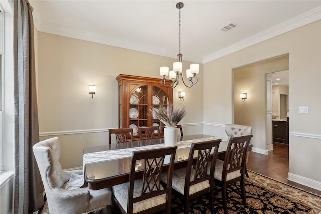 dining space featuring a notable chandelier, dark wood finished floors, baseboards, visible vents, and ornamental molding