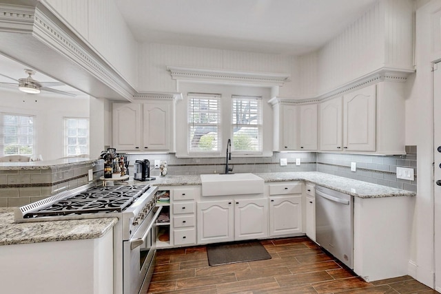 kitchen with dark wood-style flooring, appliances with stainless steel finishes, tasteful backsplash, a sink, and white cabinetry