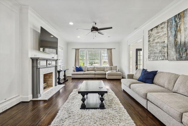 living room with a ceiling fan, crown molding, dark wood finished floors, a fireplace with raised hearth, and recessed lighting