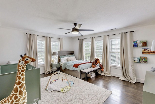 bedroom with visible vents, baseboards, dark wood-type flooring, a textured ceiling, and a ceiling fan